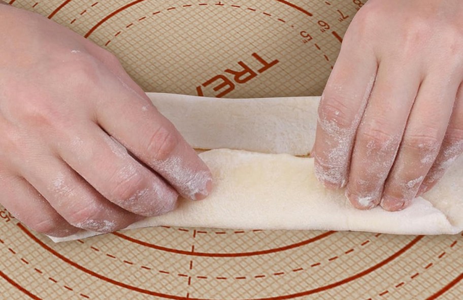 person folding bread dough on a silicone baking mat