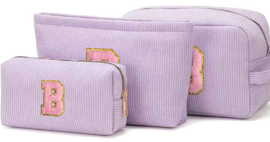 3 purple makeup bags with pink initials on them