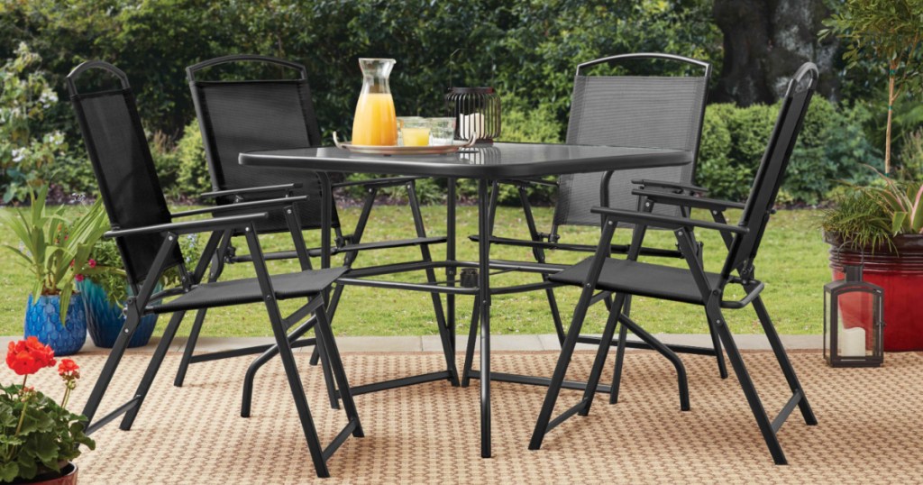 black patio set outside in front of grass and trees