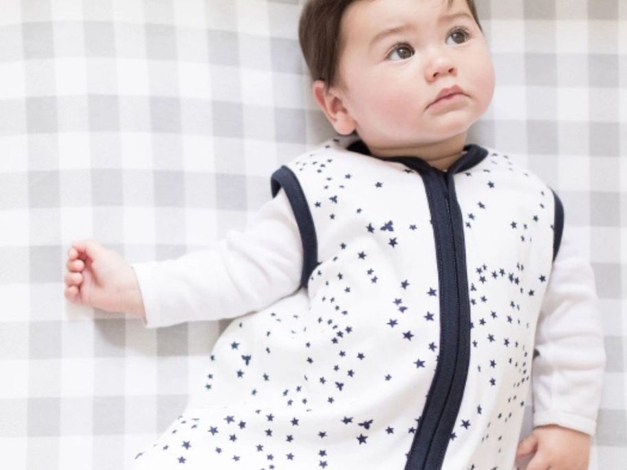 A sweet baby in a crib wearing a white and navy sleeper