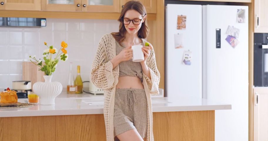 Woman wearing a duster and Ekouer women's 2-piece lounge set while standing in a kitchen holding a coffee mug