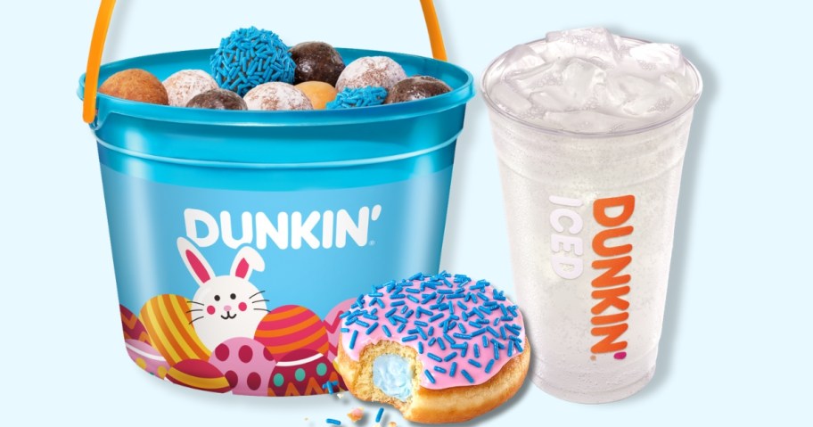 a blue bucket filled with Dunkin mini donut holes, a donut with a bite out of it and a drink in a plastic Dunkin cup