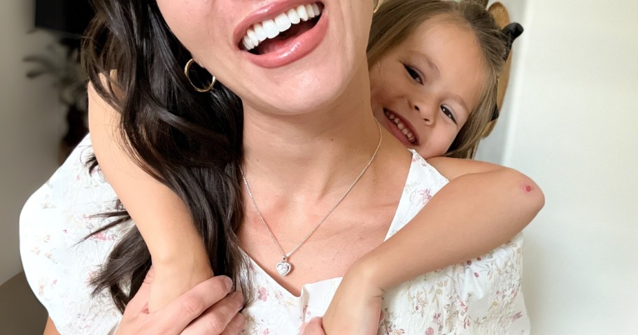 a woman smiling while her little girl hugs her from behind