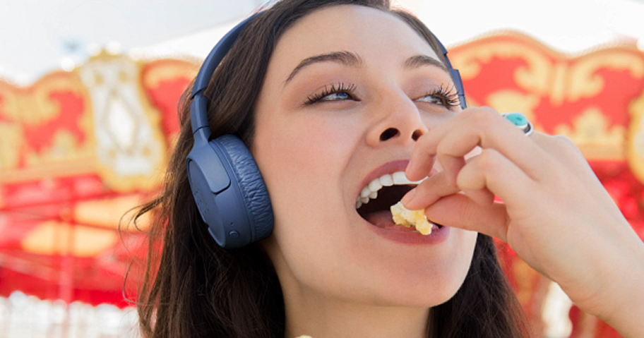 woman wearing blue JBL headphones while eating popcorn
