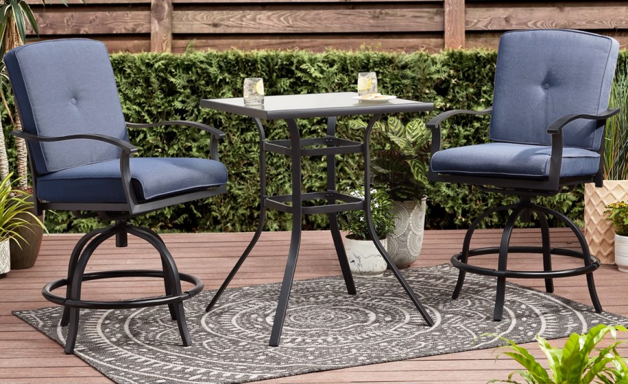 two tall patio chairs with blue cushions and glass table