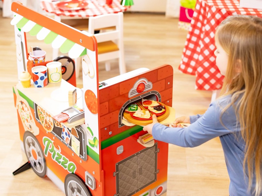 girl placing a pizza into oven on pizza food truck toy