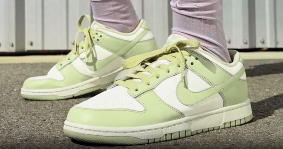 Woman's feet wearing olive green and white nike dunks