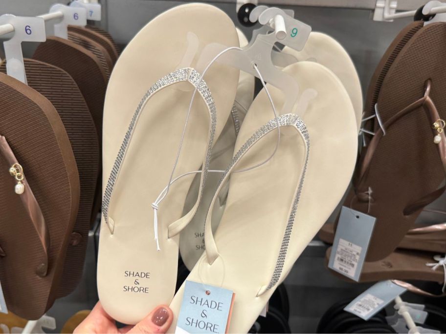 Hand touching a pair of Shade & Shore Women's Cali Flip Flop Sandals with rhinestones on the straps