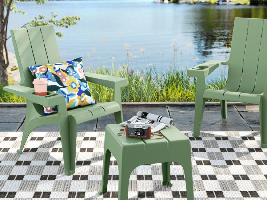 green adirondack chairs and table in front of a lake