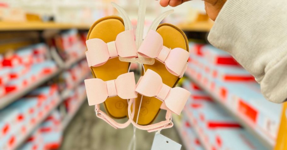 pink Cat & Jack Toddler Ruby Bow Sandals hanging from hands in store