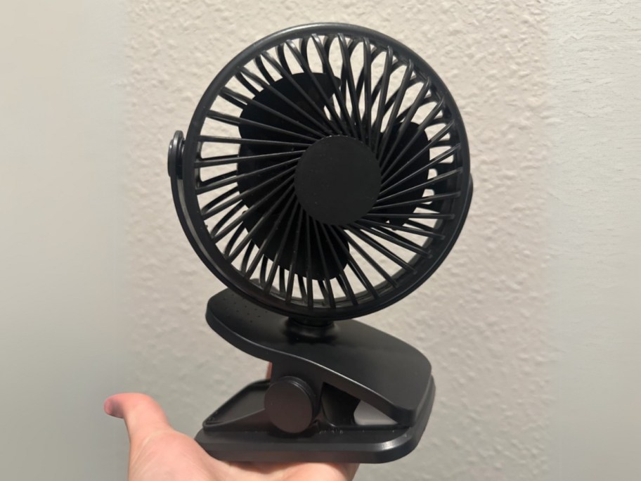 hand holding a black clip on mini portable fan