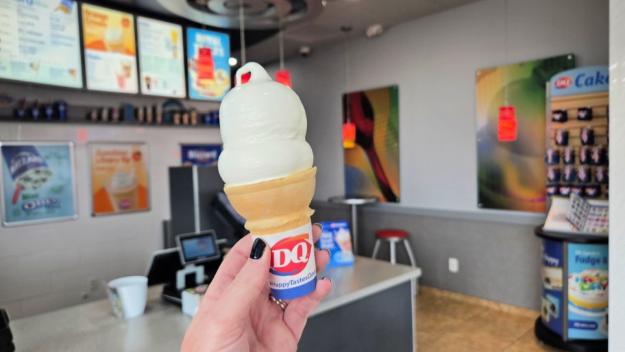 hand holding up an ice cream cone inside a dairy queen restaurant