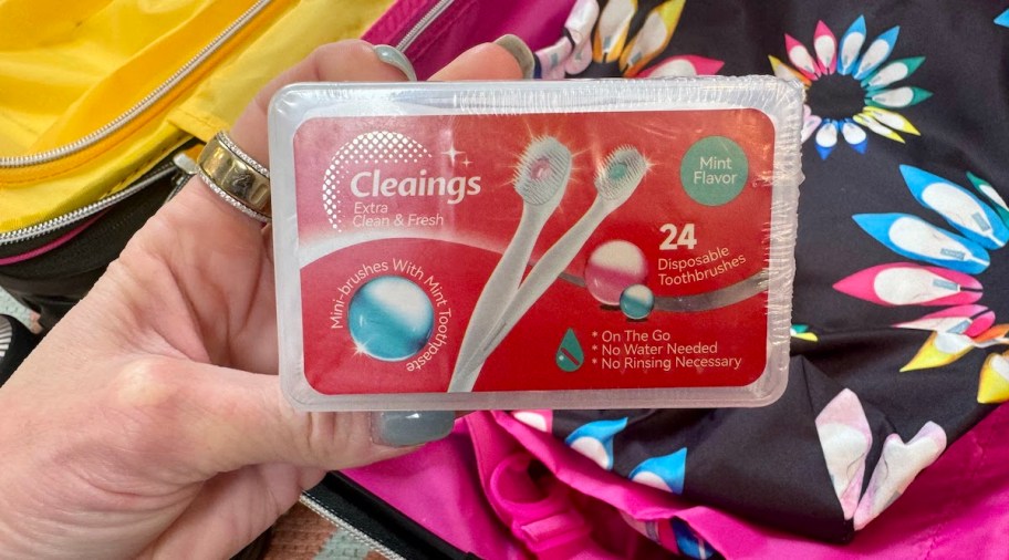 hand holding mini colgate toothbrushes