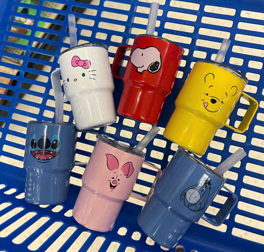 collection of mini tumblers with characters like piglet, snoopy, and stitch on them, all laying in a store shopping cart