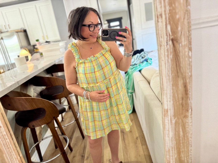 woman taking selfie in mirror wearing yellow plaid dress