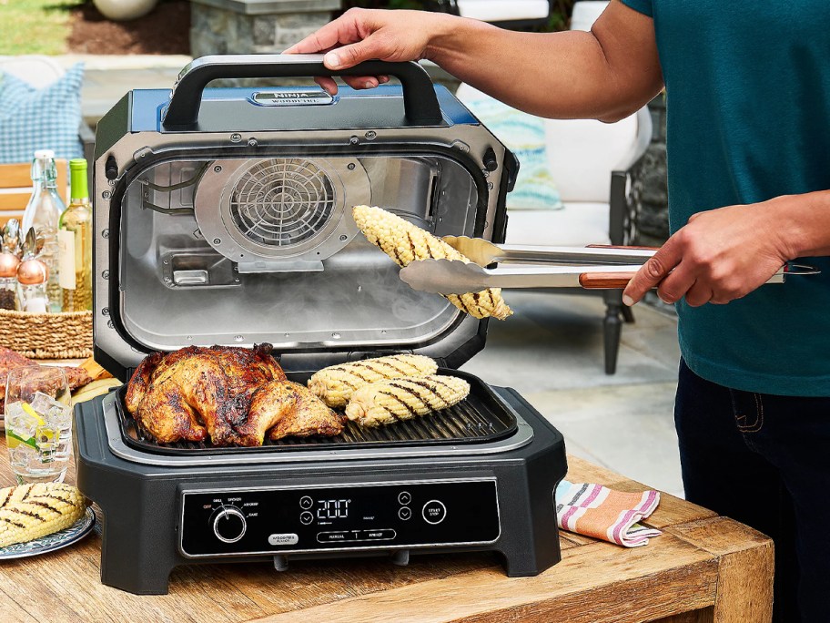 person grilling chicken on ninja grill