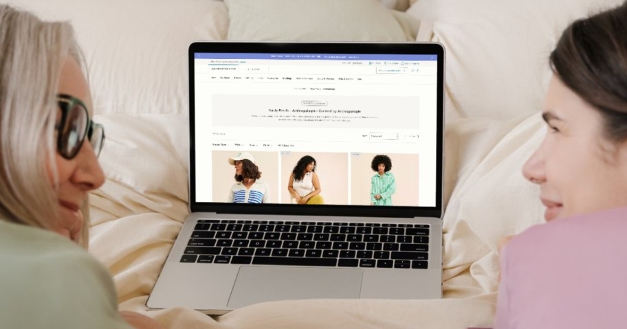 two women smiling on bed with laptop and nuuly resale on screen