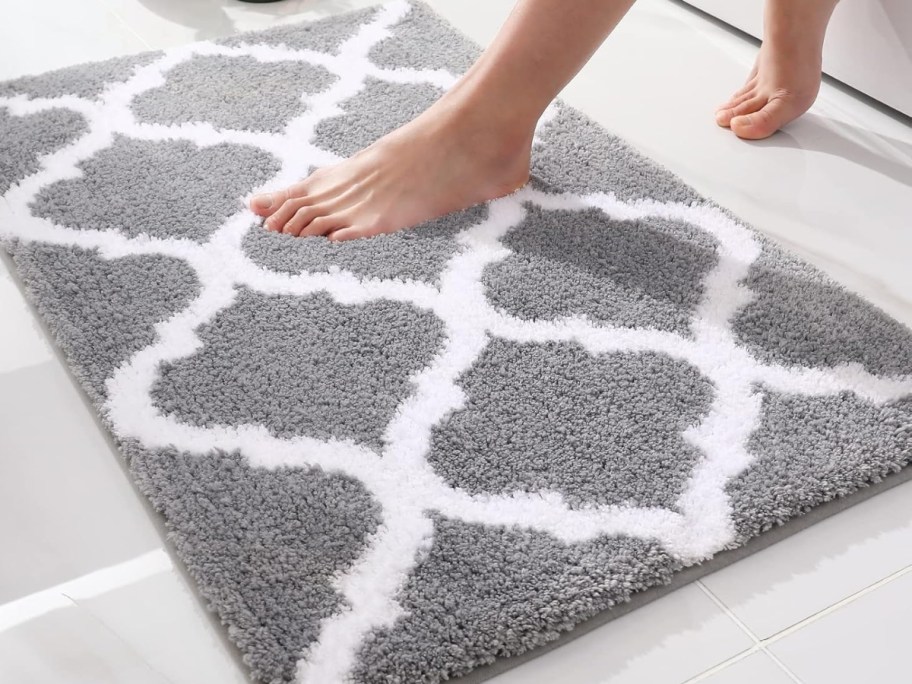 woman's feet stepping onto a grey and white trellis design bath mat