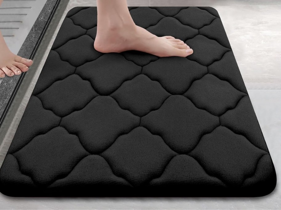 woman's feet stepping out of a shower onto a black bath mat
