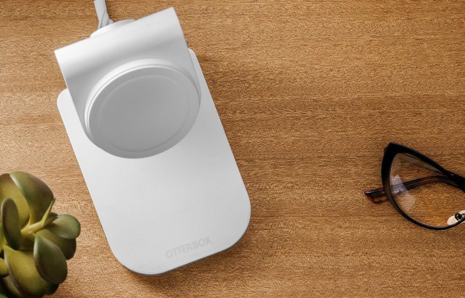 otterbox magsafe charging stand on a table near a pair of glasses and a plant