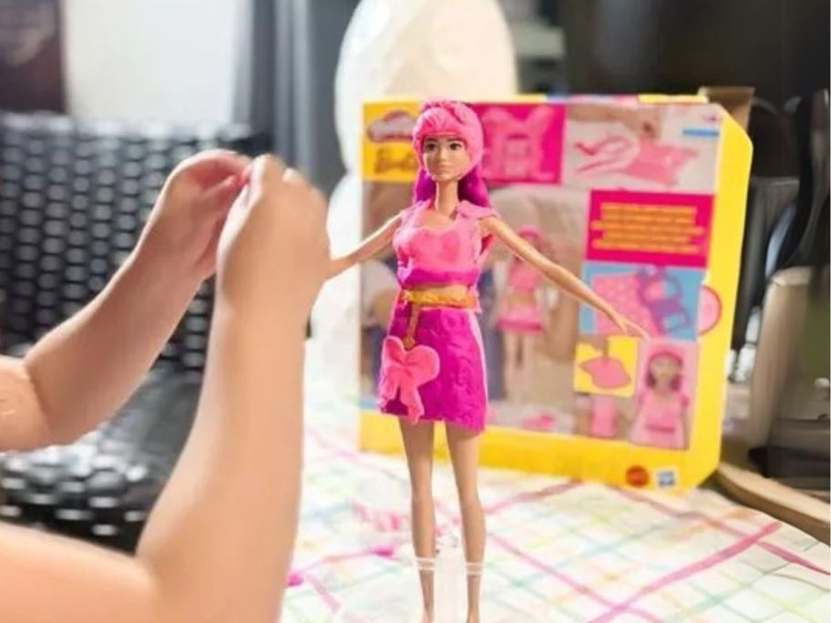 girl playing with play doh barbie on table