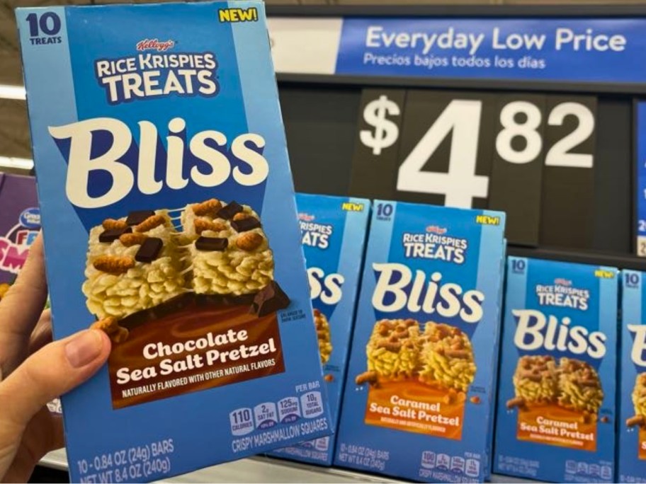 hand holding a box of Rice Krispie Treats Bliss bars, more on a store shelf behind it with a price sign that says $4.82