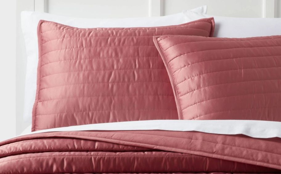 two rose colored satin pillow shams on a bed