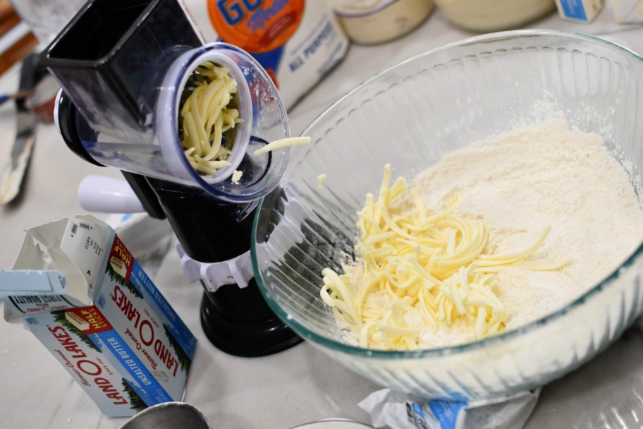 shredding cold butter into a mixing bowl 