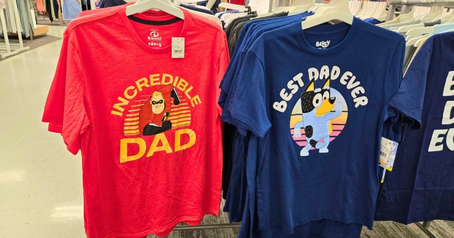 2 Dad t-shirts hanging on a store rack, one is red with Mr. Incredible and says "Incredible Dad" and the other is blue with Bluey and says "Best Dad Ever"