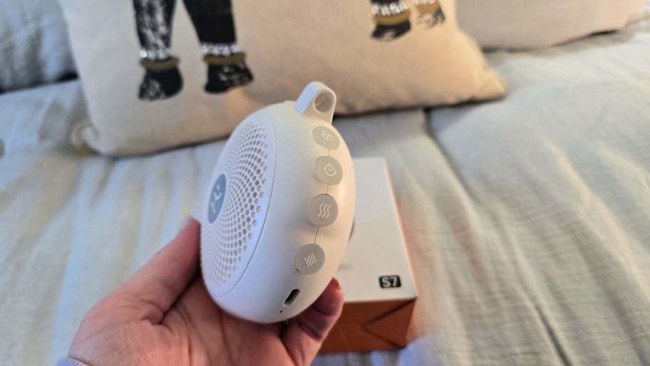 hand holding a white noise machine on its side to show the buttons