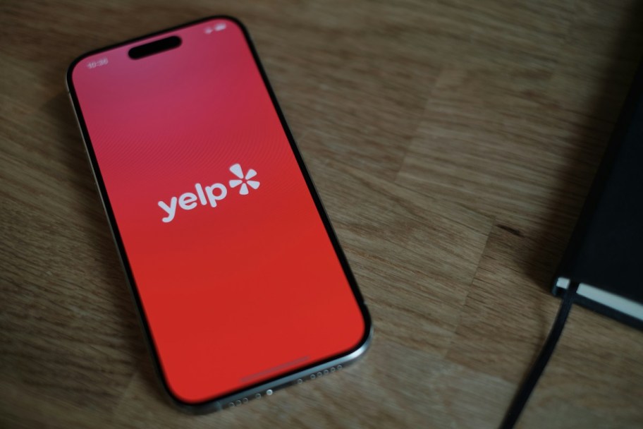 phone on wood table with yelp app on screen