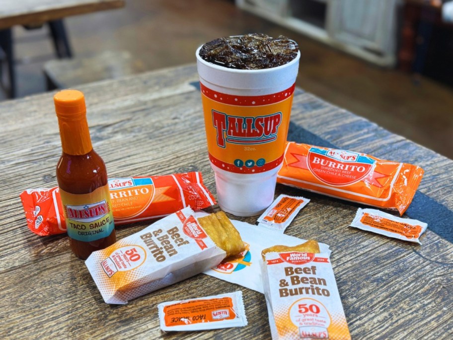 burritos on a table next to a large fountain soda