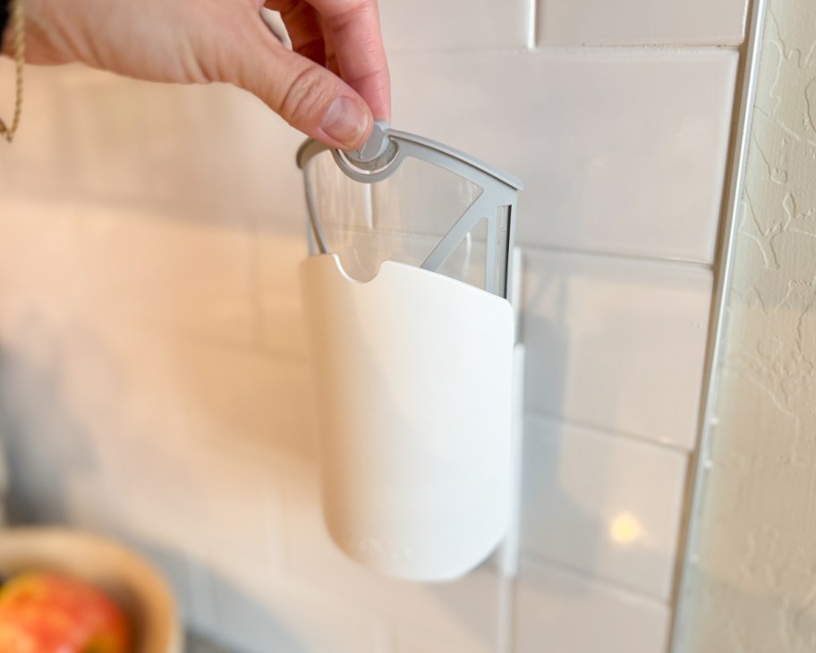 hand grabbing clear sticky fly trap from behind wall plug