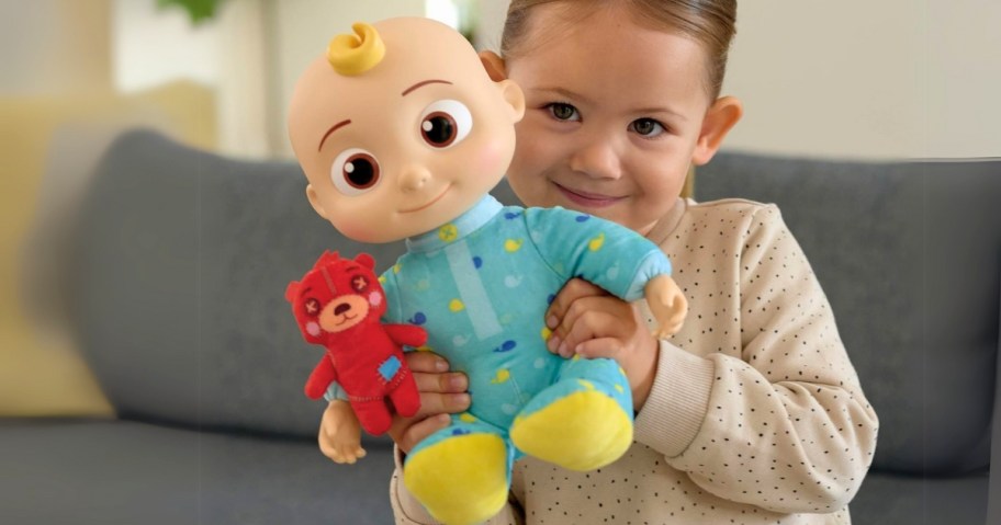 little girl holding a plush CoComelon JJ doll