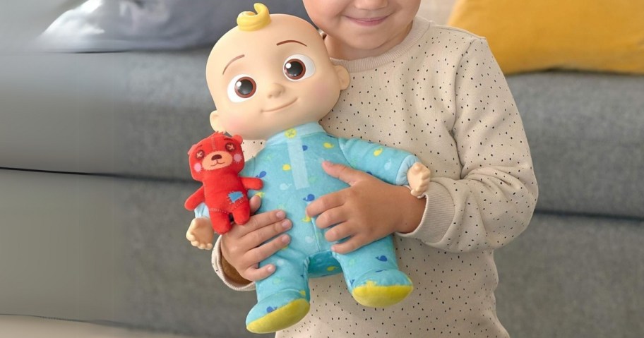little girl holding a plush CoComelon JJ doll