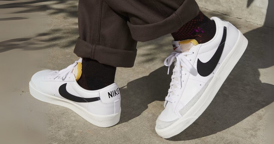 person's feet wearing white with black accents Nike Blazer low shoes