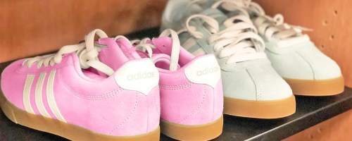 pairs of pink and light blue suede adidas sneakers on shelf in store
