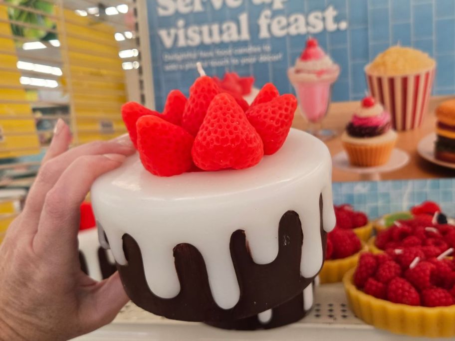 A candle that looks like a cake with strawberries on it 