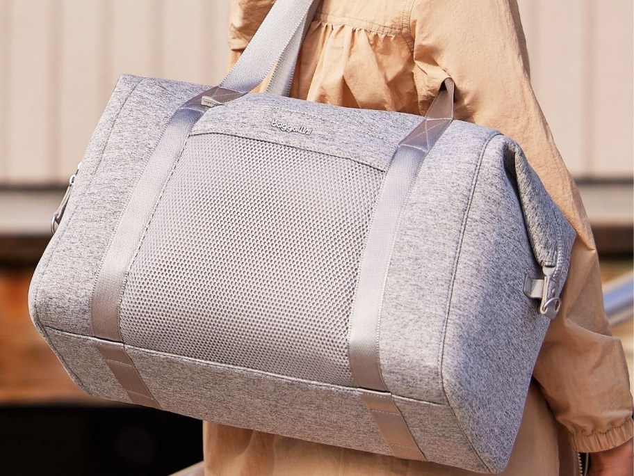 woman with a large grey duffle bag on her shoulder