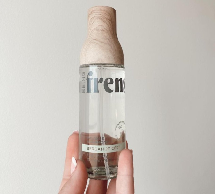 hand holding Being Frenshe Hair, Body & Linen Mist Body Spray bottle