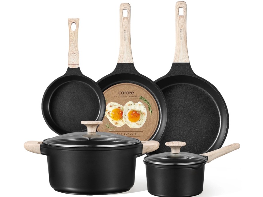 Carote Taupe Granite cookware set with black nonstick pots and pans, light wood-look handles, and glass lids, including three frying pans and two lidded saucepots.