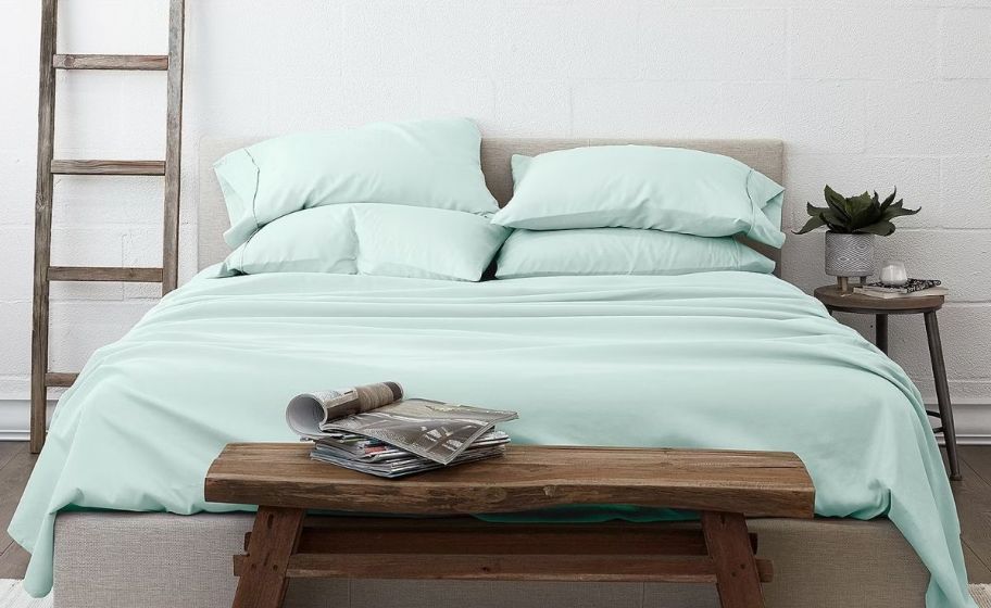 a bed made with a set of mint green sheets