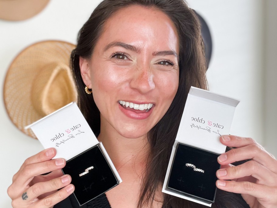woman wearing hoop earrings holding two boxes of earrings