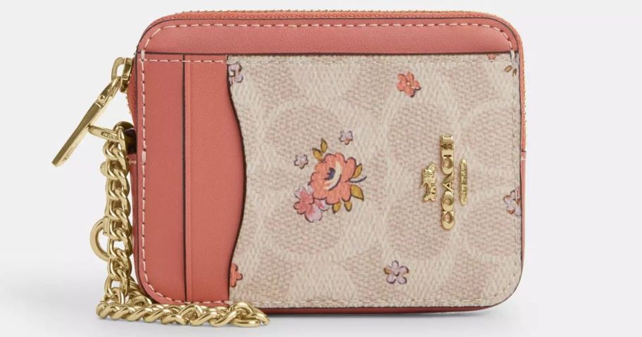 A small Coach card case in orange and floral print