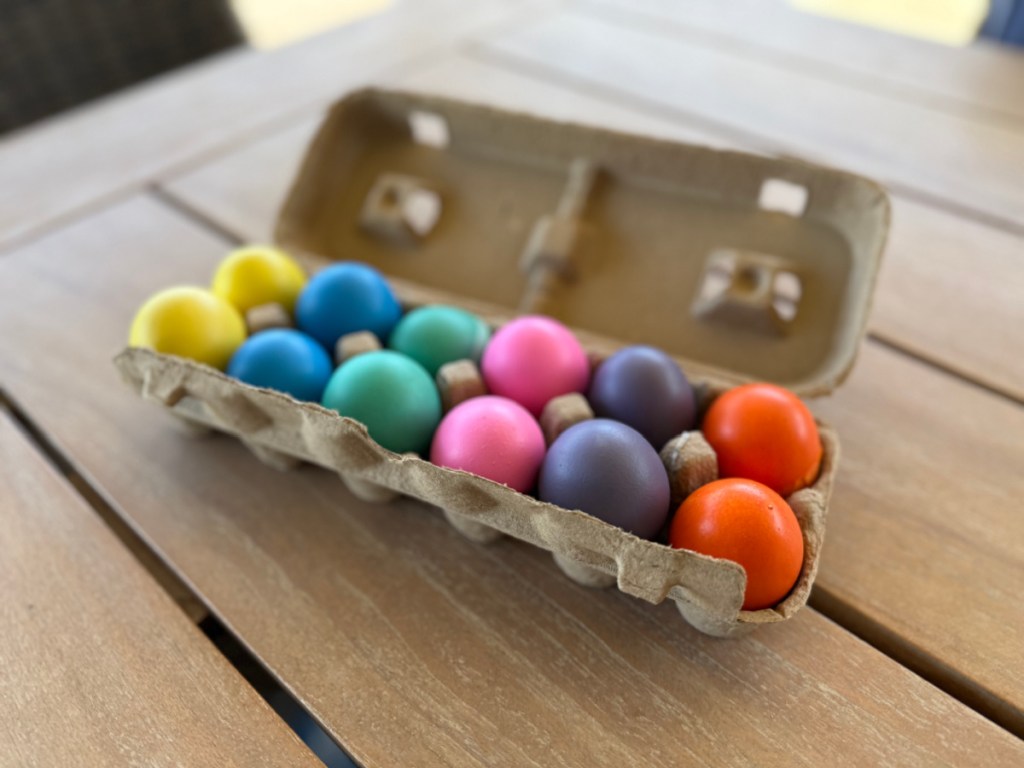 Different colored Easter confetti eggs in egg carton open on top of picnic table