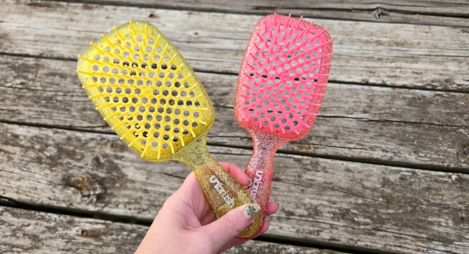 hand holding a yellow and pink unbrushes in front of their deck