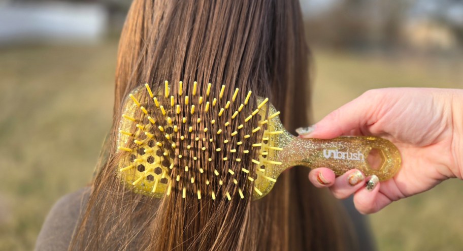 hand brushing through hair using a yellow unbrush 