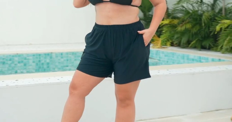 a woman wearing a navy swim top and shorts beside a small swimming pool