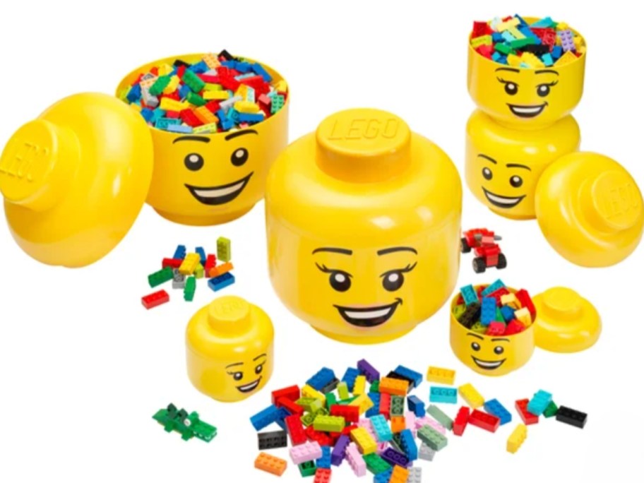 large, medium, and small LEGO head storage containers and LEGO's laying around them