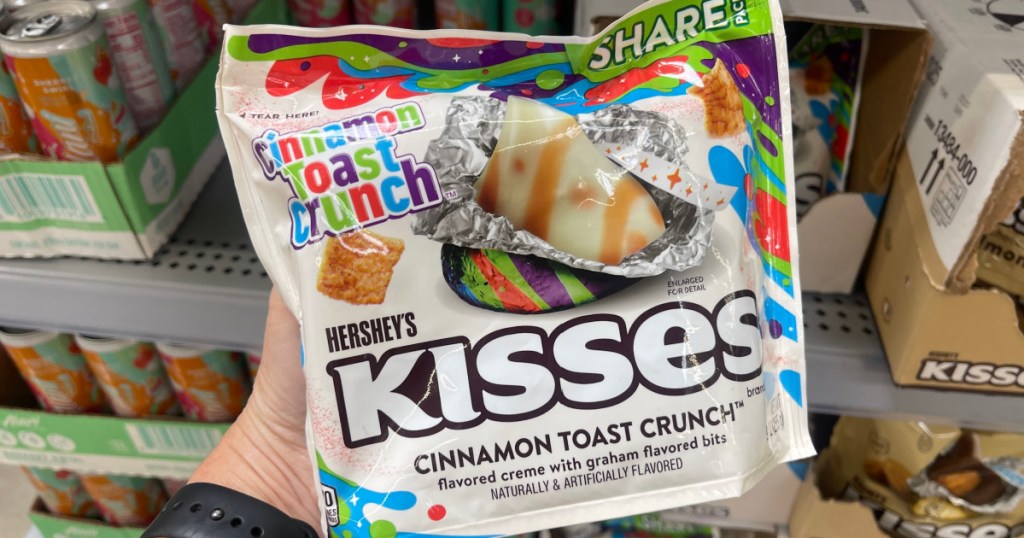 Person holding up shareable size of Hershey's kisses, cinnamon toast, crunch inside grocery store